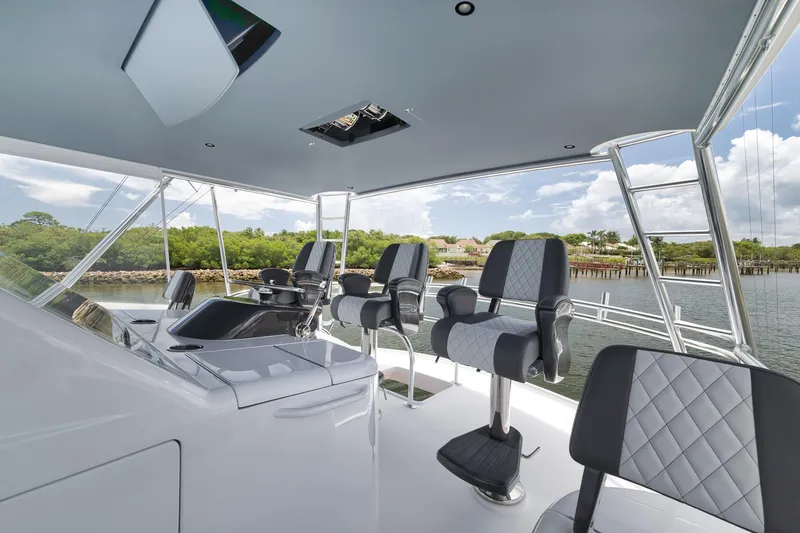 Slide: The Image of 2024 Viking 72 Convertible yacht helm with luxurious seating and scenic waterway view. - 13