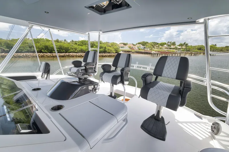Slide: The Image of 2024 Viking 72 Convertible yacht helm with luxurious seating and scenic waterfront view. - 14