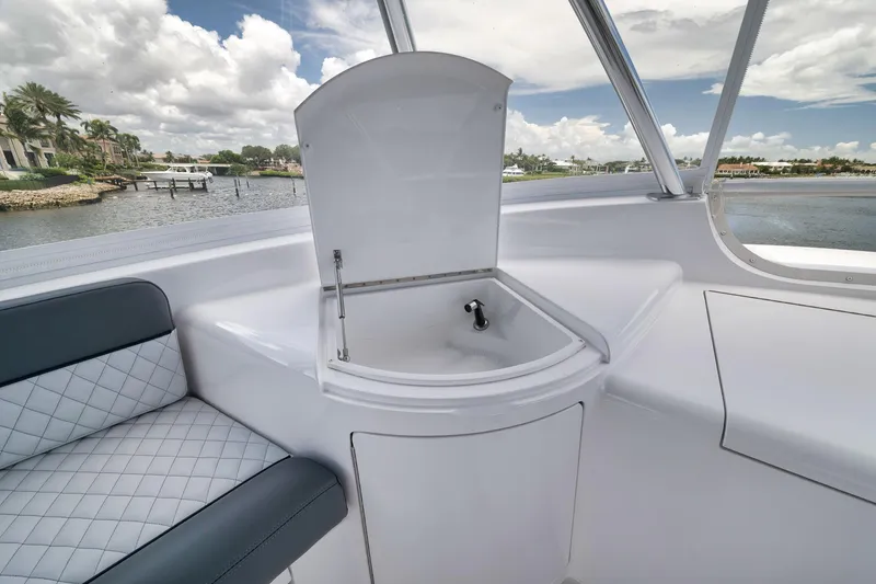 Slide: The Image of 2024 Viking 72 Convertible yacht interior with sink and seating, overlooking a scenic waterfront. - 17