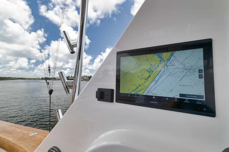 Slide: The Image of 2024 Viking 72 Convertible yacht with Garmin navigation display, docked by calm waters under a cloudy sky. - 21