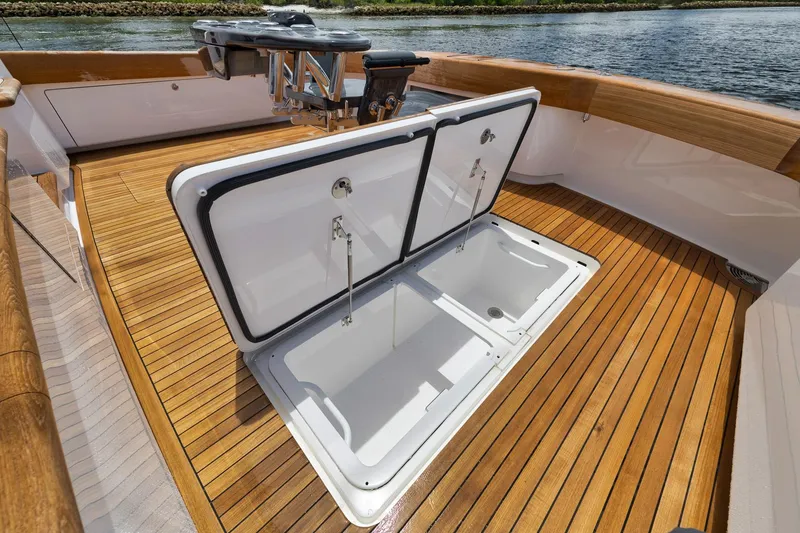 Slide: The Image of 2024 Viking 72 Convertible yacht with open storage hatch on teak deck. - 24
