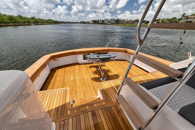 Slide: The Image of 2024 Viking 72 Convertible yacht deck with wooden flooring and scenic water view. - 31