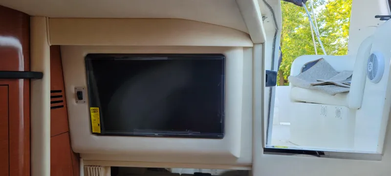 Slide: The Image of Interior view of a 2005 Sea Ray 320 Sundancer with a mounted TV and open cabin door. - 11