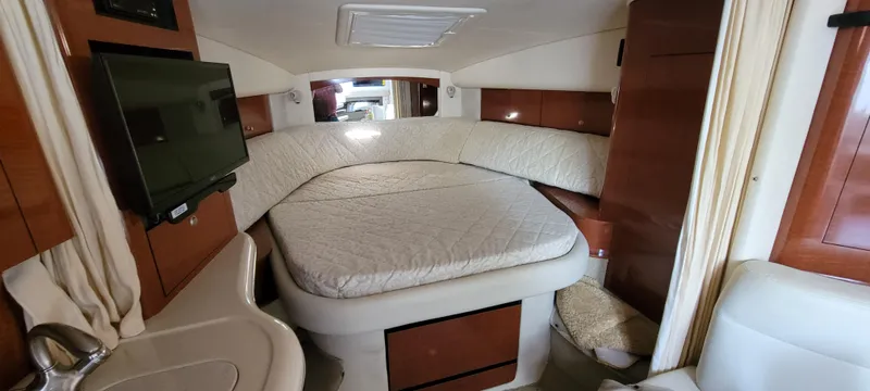 Slide: The Image of 2005 Sea Ray 320 Sundancer cabin interior with bed, TV, and wooden cabinetry. - 21