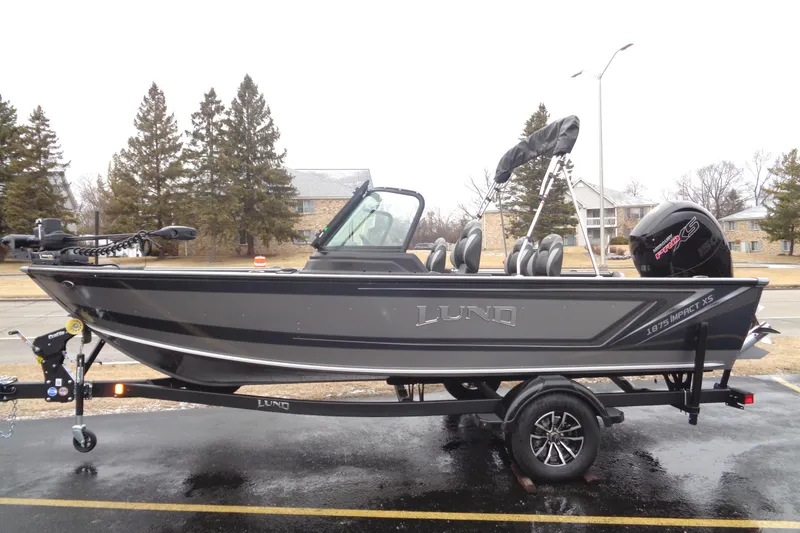 The Image of 2025 Lund 1875 Impact XS Sport boat on trailer, parked outdoors. - 0