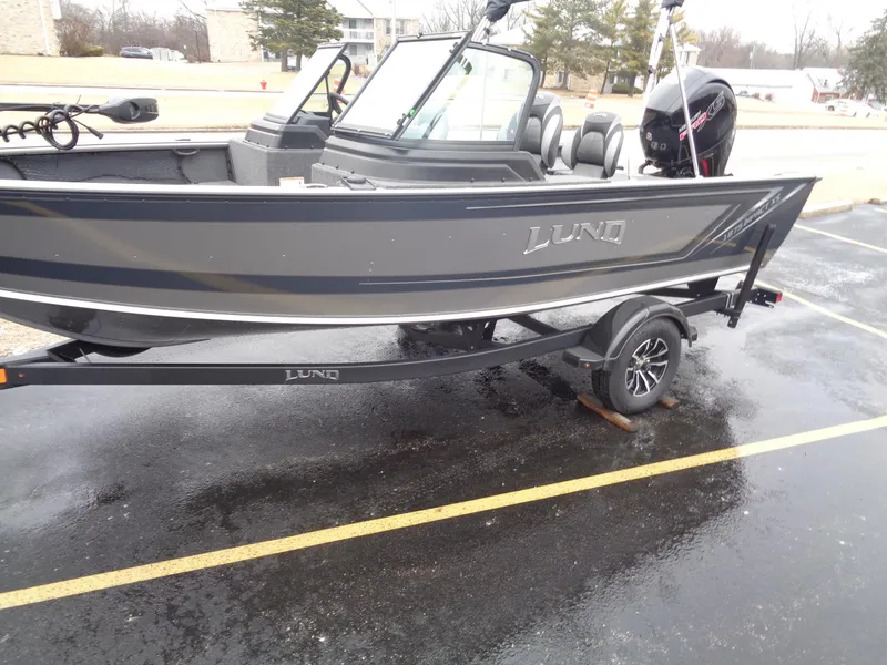 Slide: The Image of 2025 Lund 1875 Impact XS Sport boat on trailer in parking lot. - 2