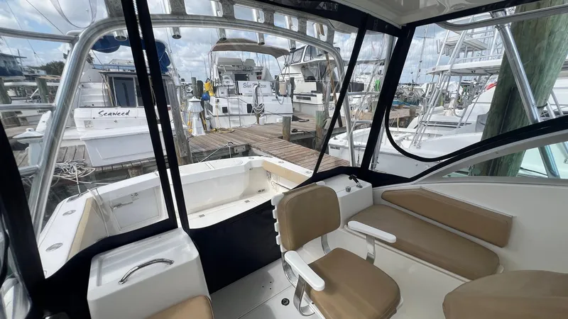 Slide: The Image of 2006 Rampage 30 Offshore boat interior at marina, featuring seating and clear windows. - 17