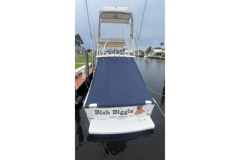 Slide: The Image of 2006 Rampage 30 Offshore boat docked, featuring blue cover and custom name "Bish Biggle." - 2