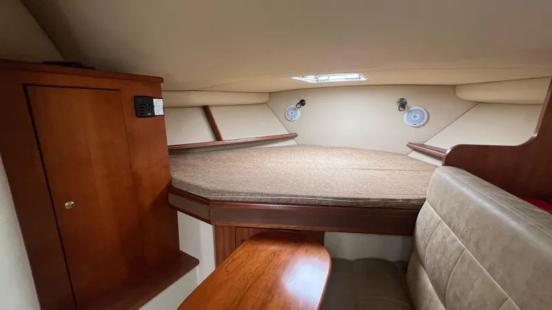 Slide: The Image of 2006 Rampage 30 Offshore cabin interior with bed, wooden cabinetry, and seating area. - 28