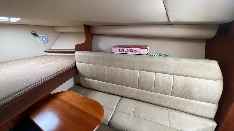 Slide: The Image of 2006 Rampage 30 Offshore cabin interior with beige seating and wooden table. - 32