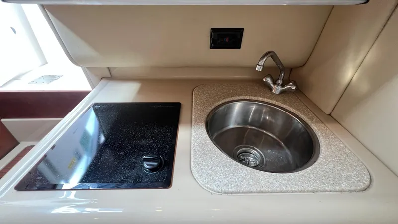 Slide: The Image of Compact kitchen area in a 2006 Rampage 30 Offshore boat, featuring a sink and stovetop. - 36