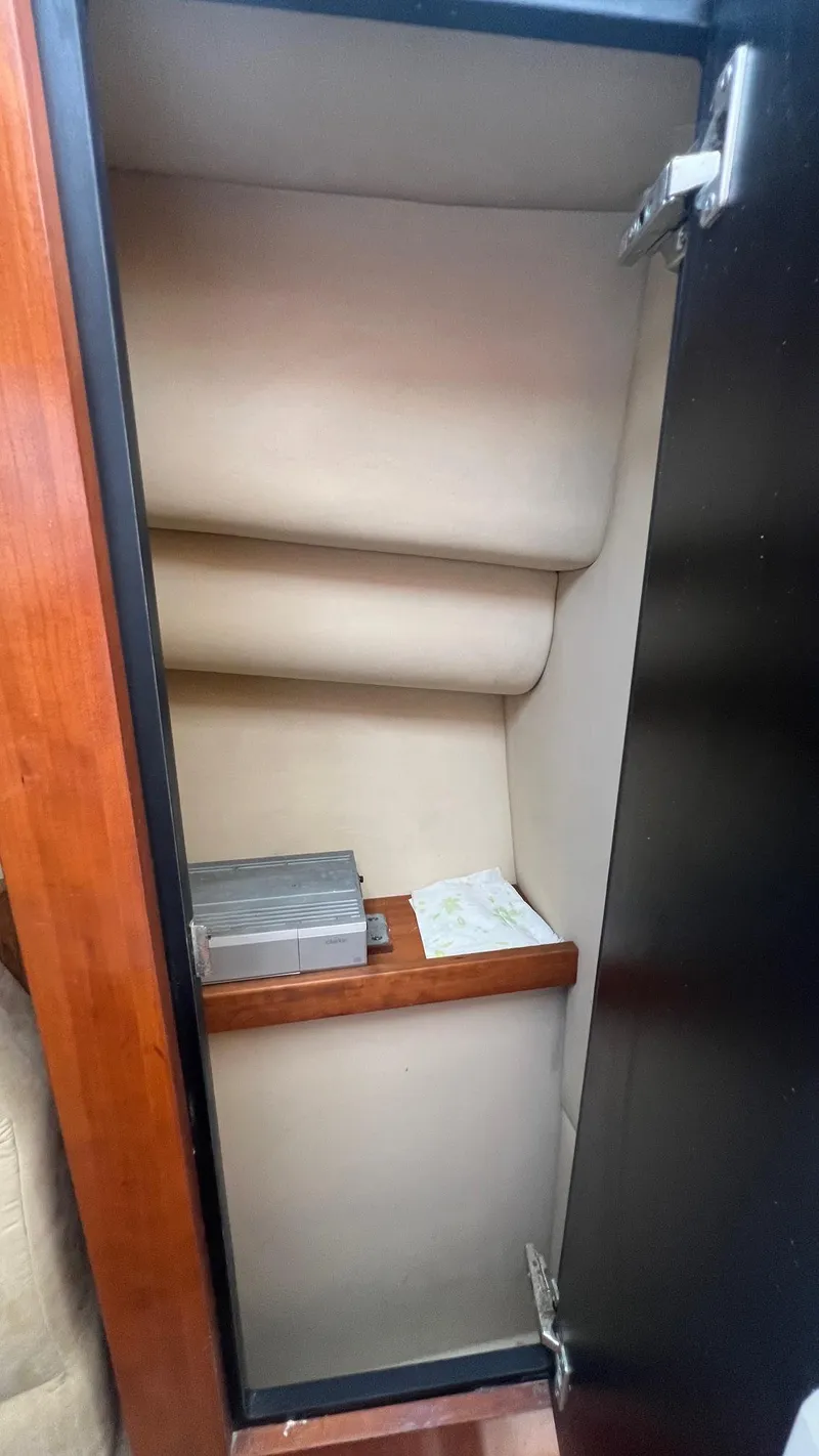 Slide: The Image of 2006 Rampage 30 Offshore cabin storage with wooden shelf and beige interior. - 40