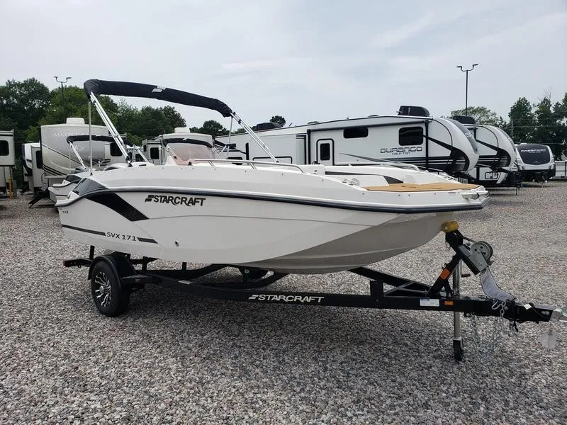 Slide: The Image of 2023 Starcraft SVX 171 OB boat on trailer, parked in a lot with RVs. - 18