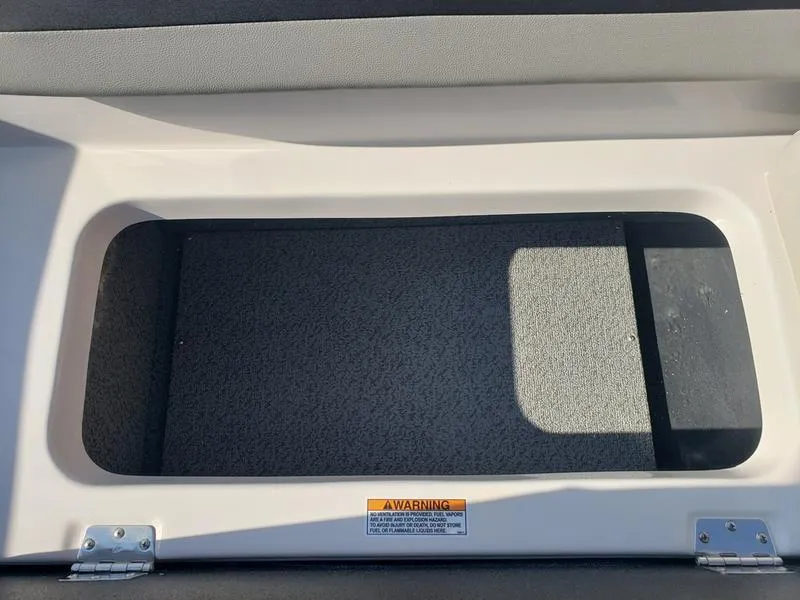 Slide: The Image of Storage compartment in 2023 Starcraft SVX191OB boat, featuring a warning label. - 12
