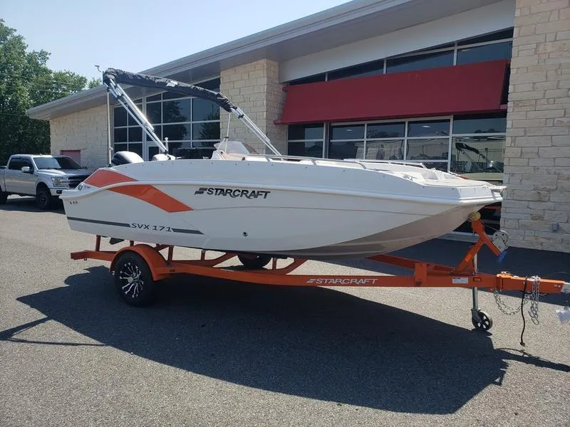Slide: The Image of 2023 Starcraft SVX 171 OB boat on orange trailer outside dealership. - 18