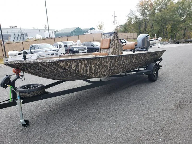 Slide: The Image of 2024 Avid Rogue 20 CC boat on trailer, camo design, parked outdoors. - 3