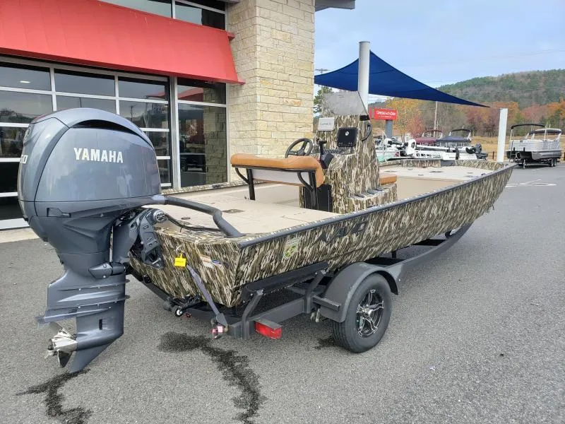 Slide: The Image of 2024 Avid Rogue 20 CC boat with Yamaha engine, camo design, parked outside dealership. - 6
