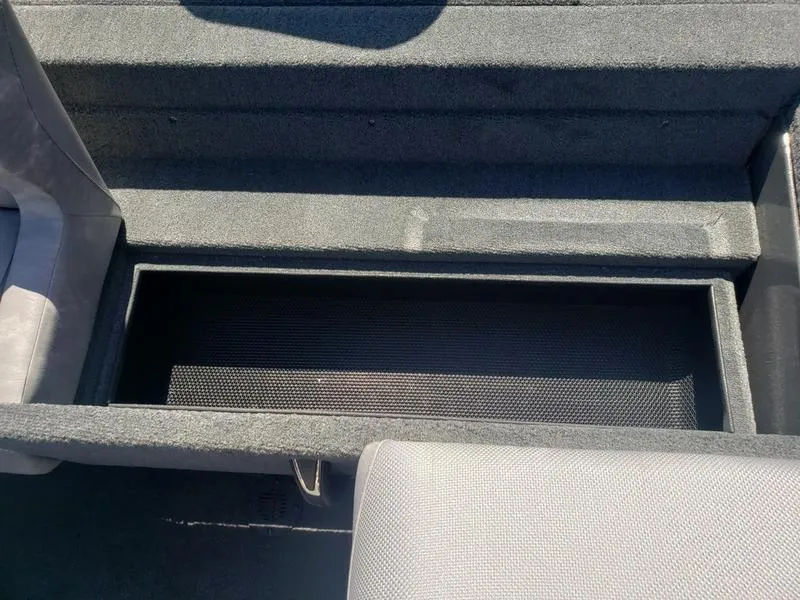 Slide: The Image of Avid 18XC 2023 boat interior storage compartment, gray upholstery, open lid view. - 12