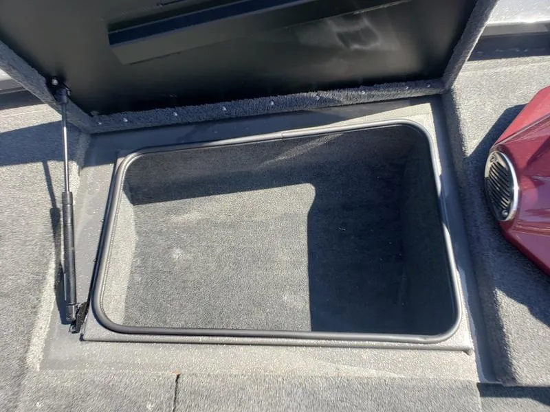 Slide: The Image of Open storage compartment in 2023 Avid 18XC boat, featuring carpeted interior and hydraulic lift. - 8