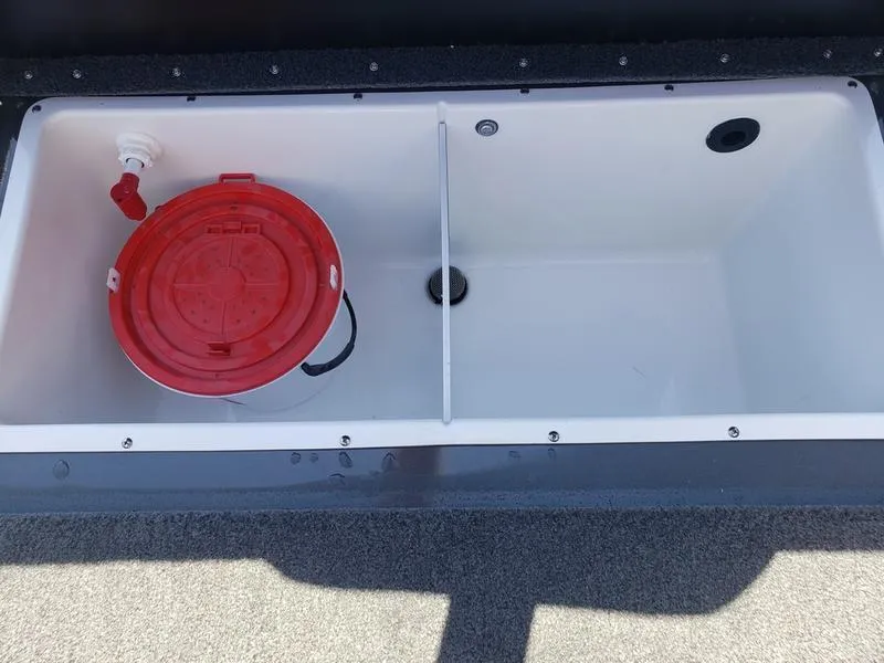Slide: The Image of Avid 18XC 2023 boat storage compartment with red bucket and divider. - 9
