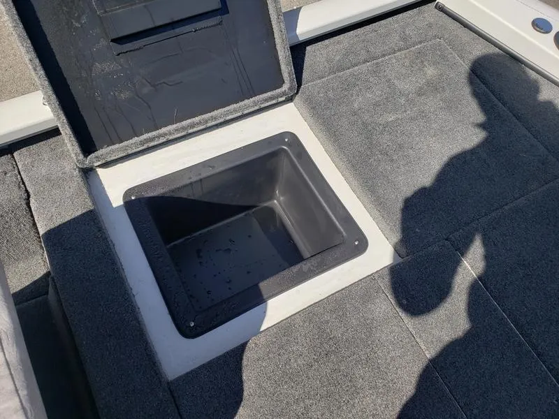 Slide: The Image of Open storage compartment on 2023 Avid 18XB boat deck, with shadow visible. - 11