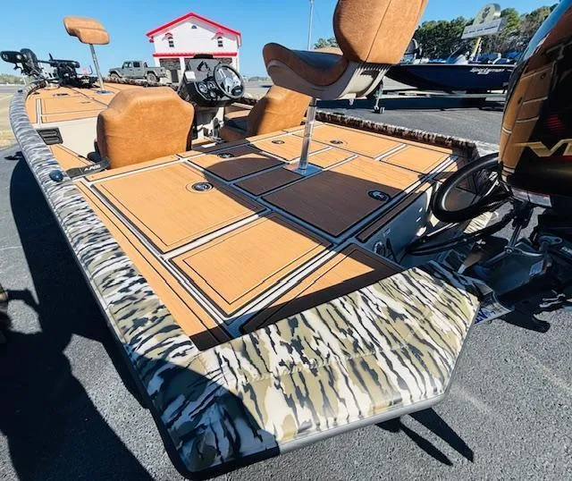 Slide: The Image of 2024 Avid 19XB boat with camo trim and tan seating, parked outdoors. - 18