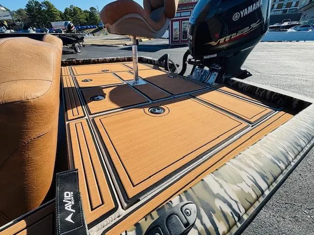 Slide: The Image of 2024 Avid 19XB boat deck with Yamaha engine, featuring tan seating and camo accents. - 19