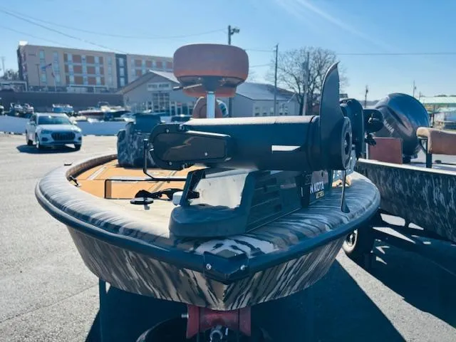 Slide: The Image of 2024 Avid 19XB boat with camouflage design, parked outdoors in a lot. - 3