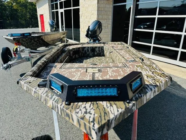 Slide: The Image of Avid 16COM 2025 camo boat with LED lights, parked outside a building. - 3