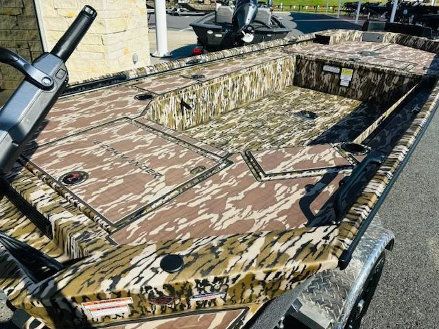 Slide: The Image of 2025 Avid 16COM boat with camouflage design, parked outdoors on a sunny day. - 7