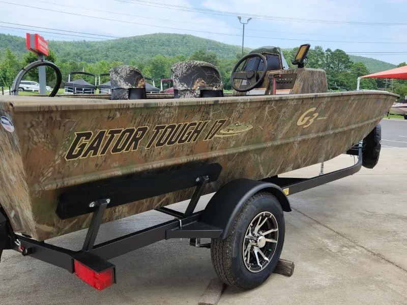 Slide: The Image of 2024 G3 17 SC boat with camouflage design on a trailer, parked outdoors. - 6