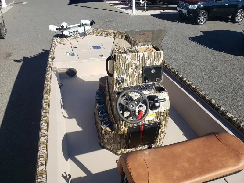 Slide: The Image of 2024 Avid Rogue 20 CC boat with camo console and seating, parked outdoors. - 24