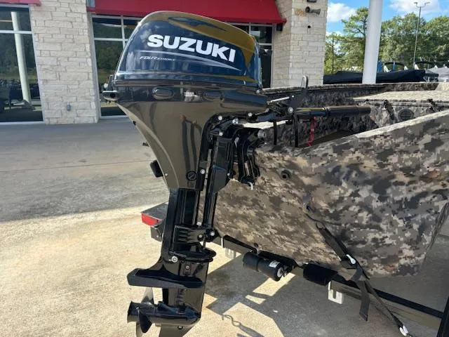 Slide: The Image of 2024 Havoc Boats 1550 VJ with Suzuki outboard motor, camo design, parked outdoors. - 10