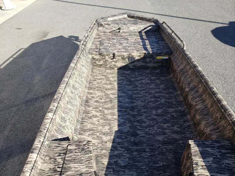 Slide: The Image of 2024 Havoc Boats 1756 Dbst with camouflage interior, parked on pavement. - 11