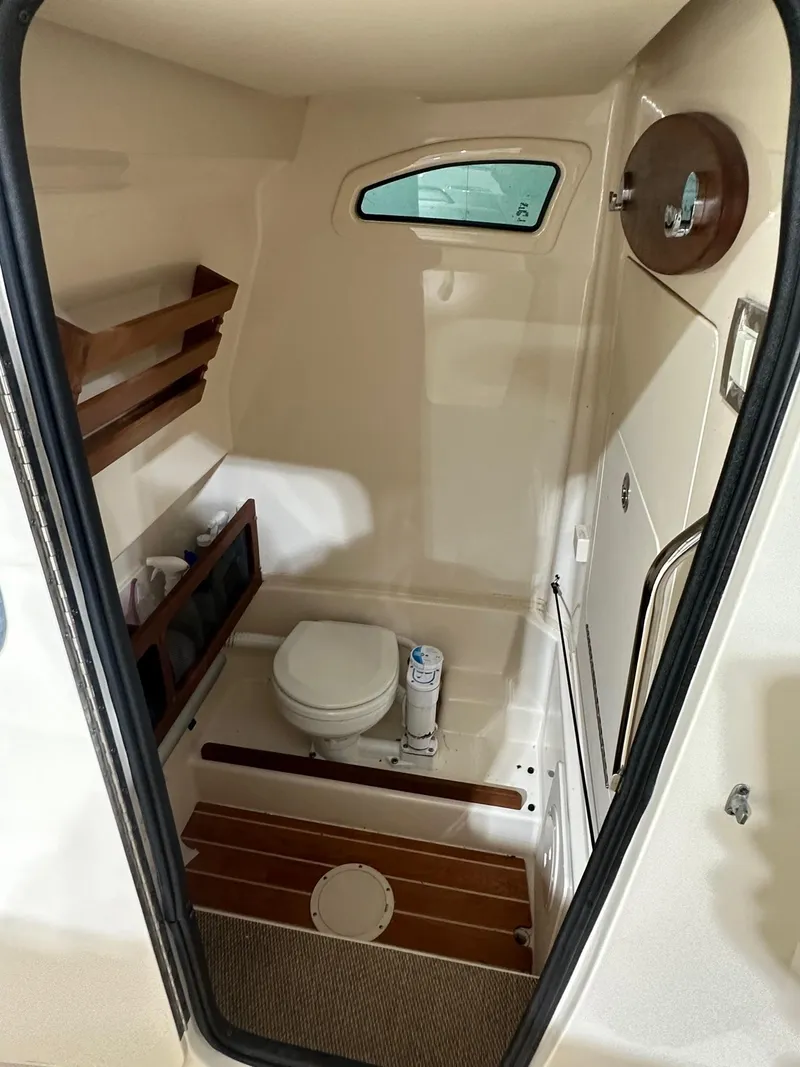Slide: The Image of 2020 Grady-White 271 Canyon boat interior bathroom with toilet and wooden accents. - 11