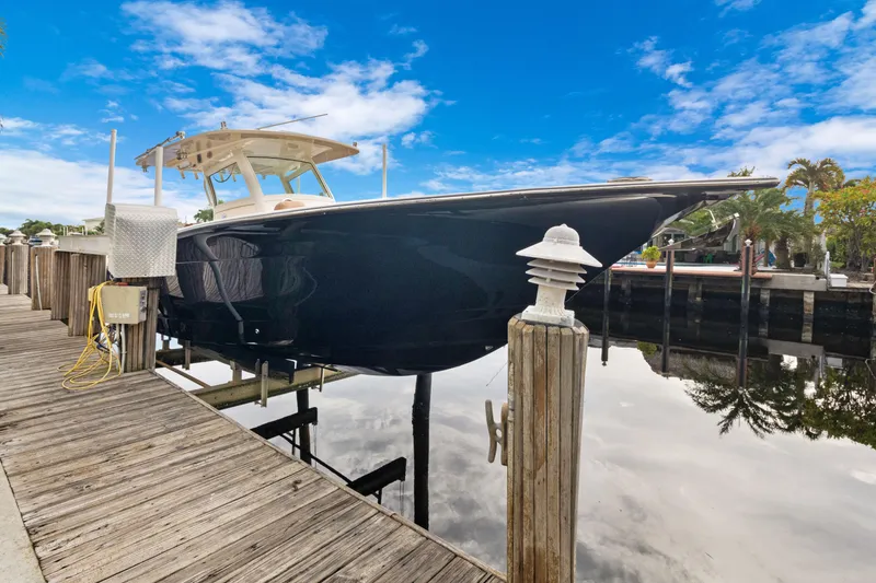 Slide: The Image of 2018 Scout 320 LXF boat docked by a wooden pier under a clear blue sky. - 1