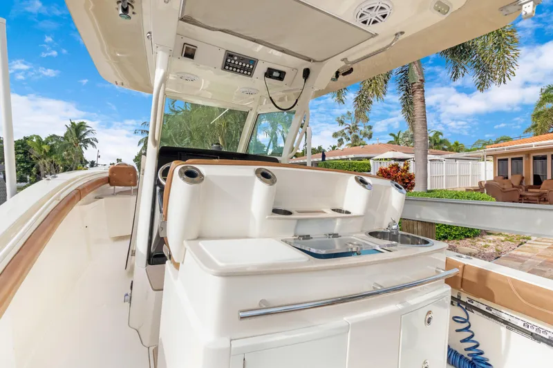 Slide: The Image of 2018 Scout 320 LXF boat interior with helm station and tropical background. - 12