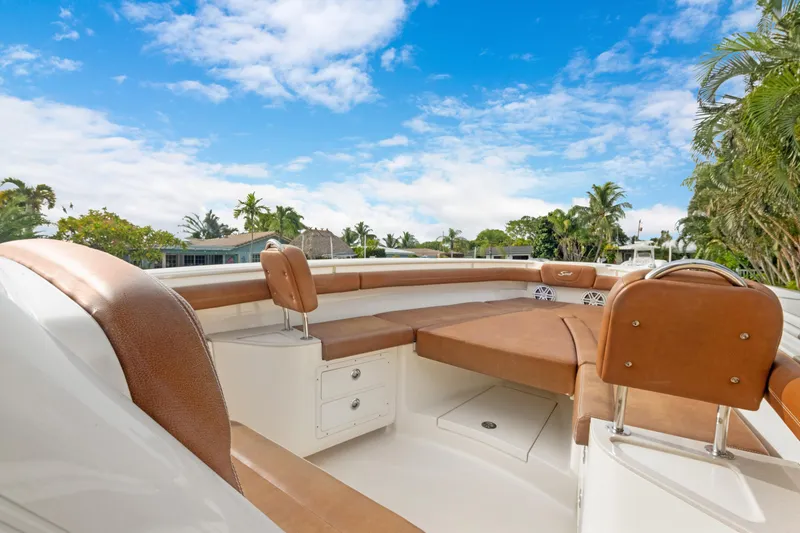 Slide: The Image of 2018 Scout 320 LXF boat interior with tan seating, under a clear blue sky. - 14