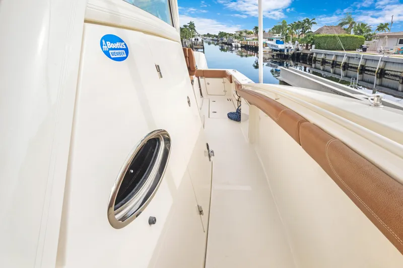 Slide: The Image of 2018 Scout 320 LXF boat deck with tan seating, docked by a canal. - 19