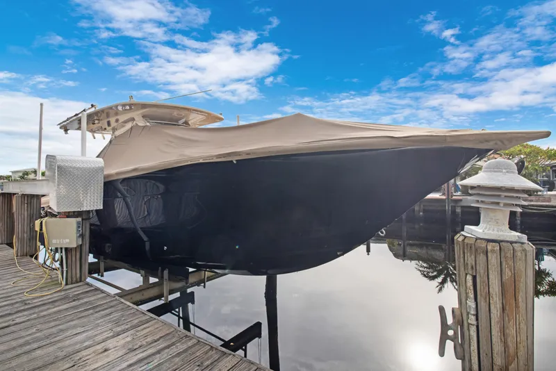 Slide: The Image of 2018 Scout 320 LXF boat docked, covered, with blue sky background. - 45