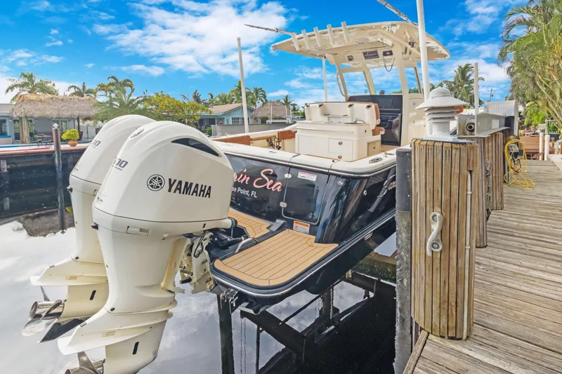 Slide: The Image of 2018 Scout 320 LXF boat docked with twin Yamaha engines, under a clear blue sky. - 48