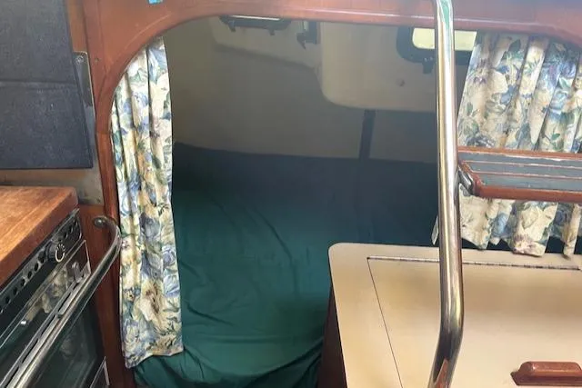 Slide: The Image of Interior cabin of a 1991 Hunter 30T sailboat with floral curtains and a green bedspread. - 10
