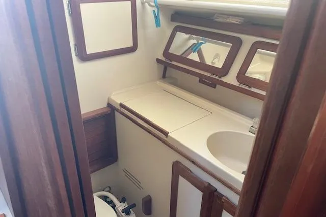 Slide: The Image of 1991 Hunter 30T yacht bathroom with sink, mirror, and wooden accents. - 12