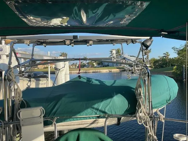 Slide: The Image of 1991 Hunter 30T sailboat with green cover docked by a calm waterway. - 28