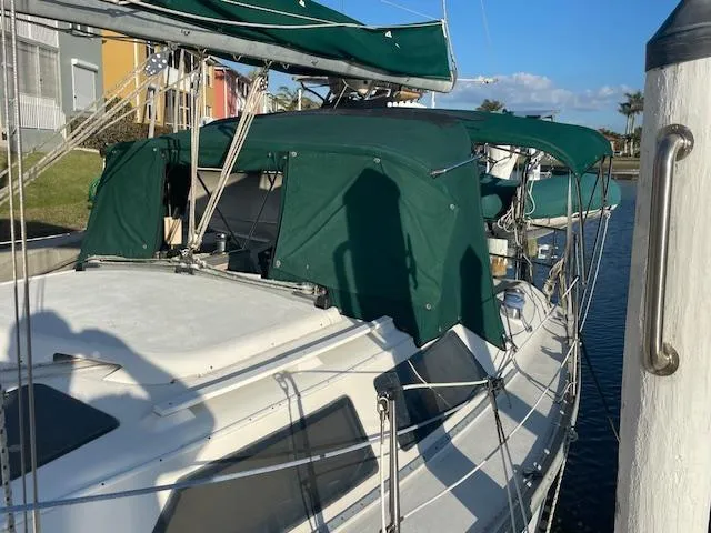 Slide: The Image of 1991 Hunter 30T sailboat docked, featuring green canvas covers and clear skies. - 29