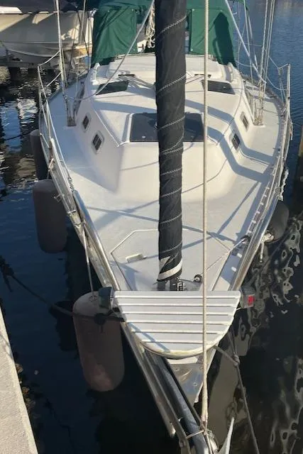 Slide: The Image of 1991 Hunter 30T sailboat docked, featuring a sleek white deck and green covers. - 32