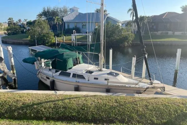 Slide: The Image of 1991 Hunter 30T sailboat docked in a serene canal setting. - 33