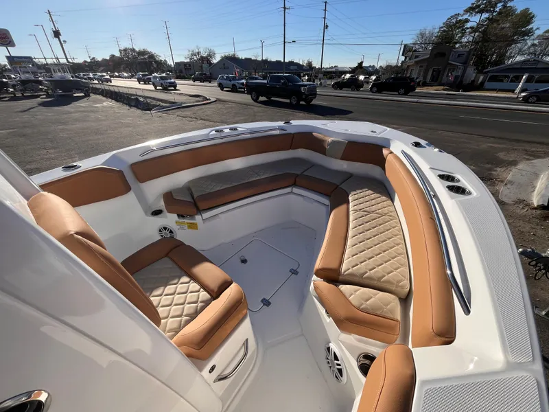 Slide: The Image of 2025 NauticStar 242L Offshore boat with tan seating, parked near a busy street. - 10