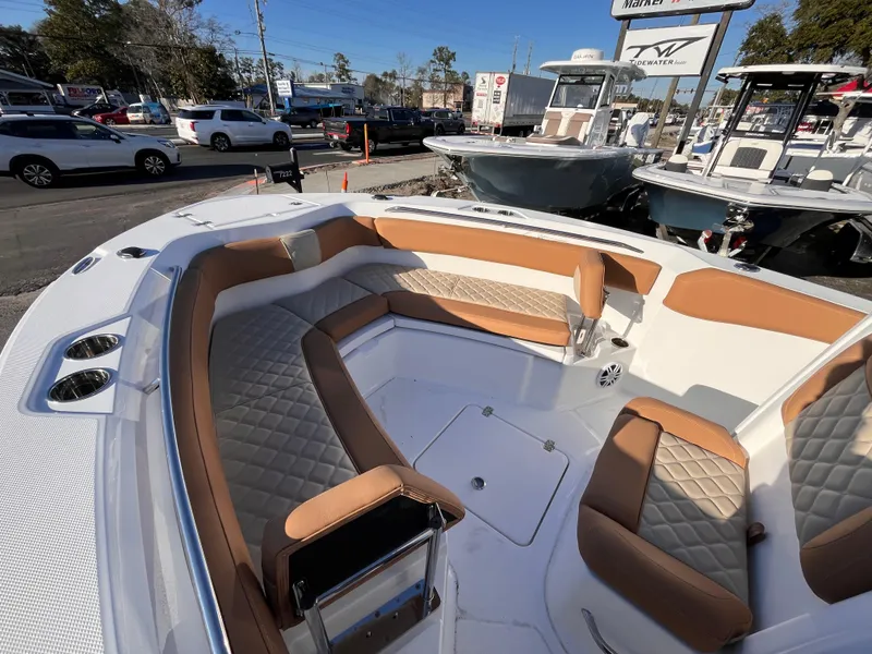 Slide: The Image of 2025 NauticStar 242L Offshore boat with tan seating, parked in a marina. - 11