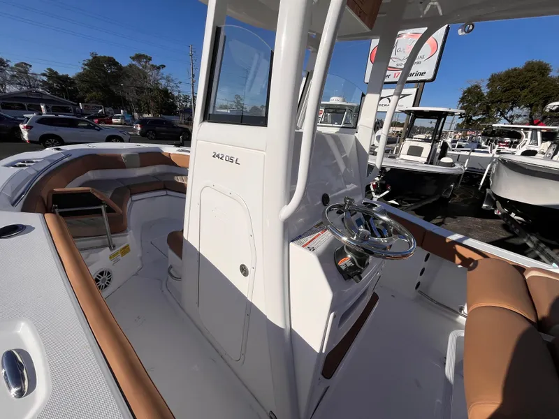 Slide: The Image of 2025 NauticStar 242L Offshore boat interior with tan seating and steering console. - 12